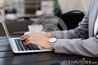 Business woman hands in suit is typing on a laptop in street cafe Stock Photo