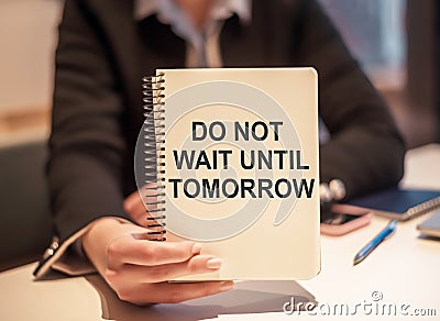 Business woman holding a notebook with the text Do not wait until tomorrow - motivational reminder Stock Photo