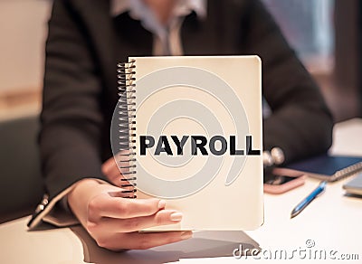 Business woman holds a notebook with the text PAYROLL Stock Photo