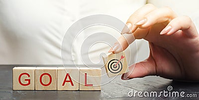 Business woman holds wooden blocks with the word Goal. The concept of achieving business goals. Reaching new heights. Execution of Stock Photo