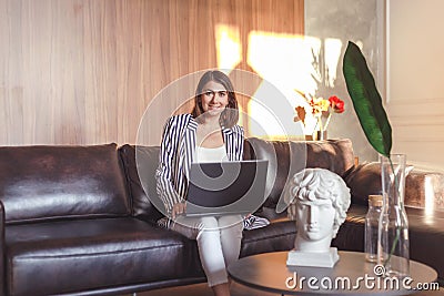 Business woman in jacket on leather sofa working in creative art office Stock Photo