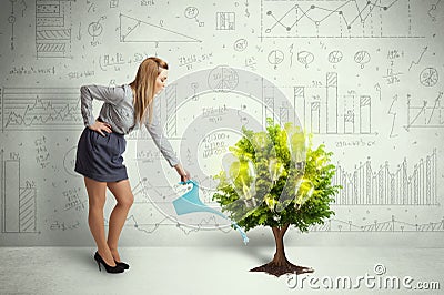 Business woman pouring water on lightbulb growing tree Stock Photo