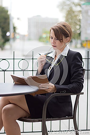 Business woman reads her notes at outdoor cafe Stock Photo