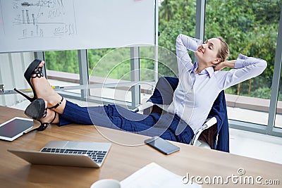 business woman relaxing or sleeping with her feet on the desk in office. female boss worker close eyes sitting with legs on the Stock Photo