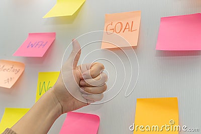 Business woman showing thumbs up with colored sheets sticky note paper on white board background Stock Photo