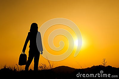 Business woman standing and holding bag at sunset silhouett. Stock Photo