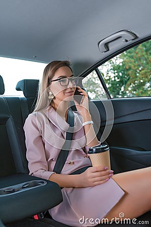 Business woman in suit, sitting VIP taxi, holding mobile phone, important call, negotiations, work on road, cup of Stock Photo