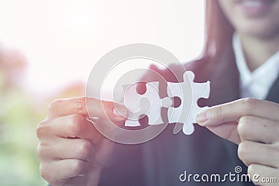 Business woman is trying to connect couple puzzle piece. Symbol of association and connection. Concept of business strategy Stock Photo