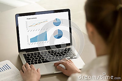Business woman working on laptop with project statistics on scre Stock Photo