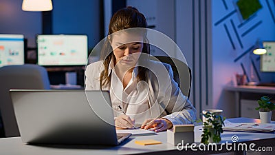 Business woman working overtime to respect deadline of project sitting in business office Stock Photo