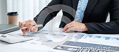 Business woman are working by reviewing the numeric data from the graph using a calculator Stock Photo