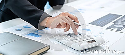 Business woman are working by reviewing the numeric data from the graph using a calculator Stock Photo