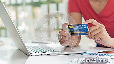 Business women hold credit cards and use laptop computers and mobile phones to shop online, e-commerce, internet banking, spend mo Stock Photo