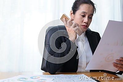 Business women holding smart phone to speak with partners, customers, team and analysis paper chart at office. Business people Stock Photo