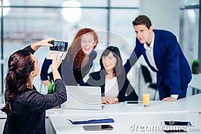 Businesswoman shooting her collegues at mobile phone camera Stock Photo
