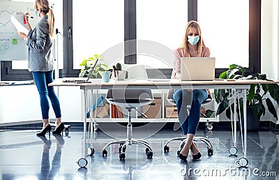 Business young women wearing a hygienic facial mask working in the office while keeping safe distances Stock Photo