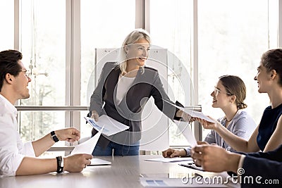 Businesslady share handout sheets materials to diverse young colleagues Stock Photo
