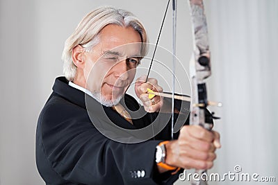 Businessman aiming at target with bow and arrow Stock Photo