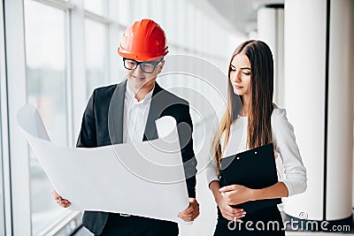 Businessman architects look at paper plan business woman architect in office to discuss business projects. Arhitect explain deatai Stock Photo