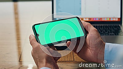 Businessman arms holding mockup smartphone indoors. Boss using green display Stock Photo