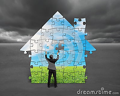 Businessman assembling house shape puzzles with nature image Stock Photo