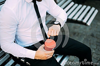 Close up Businessman On Bench With Coffee look at clock to be in time from pause at work Stock Photo