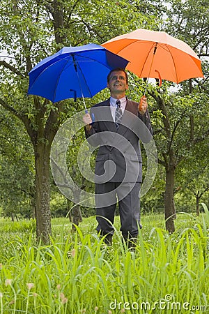 Businessman with blue and orange umbrellas Stock Photo