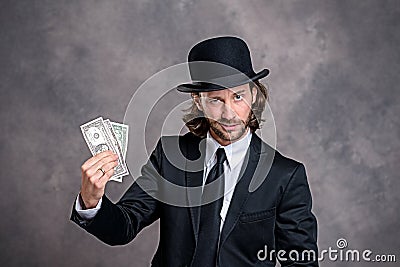 Businessman with bowler hat in black suit showing money Stock Photo