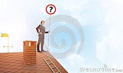 Businessman on brick house roof showing banner with question mark. Mixed media Stock Photo