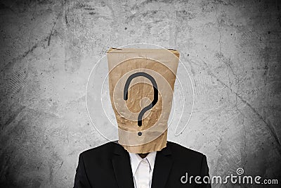 Businessman with brown paper bag on head, with question mark, on concrete texture background Stock Photo