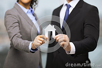 Businessman and businesswoman holding white house Stock Photo