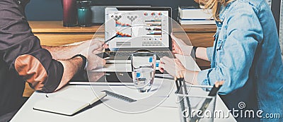 Businessman and businesswoman sitting at table in front of laptop and working.Graphs,charts and diagrams on PC screen. Stock Photo