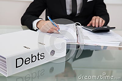 Businessman calculating debts at desk Stock Photo