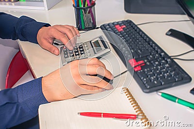 Businessman calculating the financial statements. Close up young man with calculator counting making notes at home Stock Photo