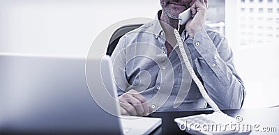 Businessman on call in front of laptop at office desk Stock Photo
