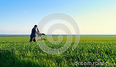 Businessman carries an office chair in a field to work, freelance and business concept, green grass and blue sky as background Stock Photo