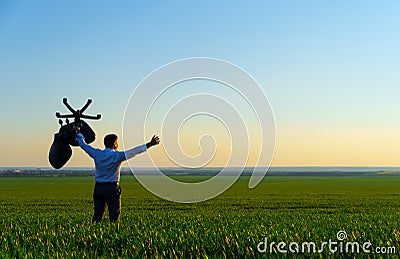 Businessman carries an office chair in a field to work, freelance and business concept, green grass and blue sky as background Stock Photo