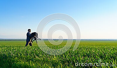 Businessman carries an office chair in a field to work, freelance and business concept, green grass and blue sky as background Stock Photo