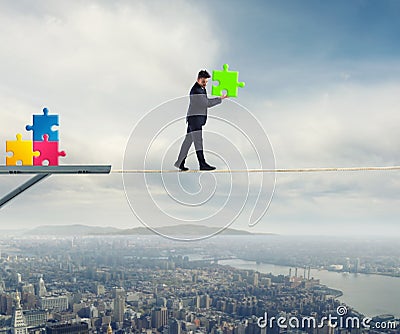 Businessman carries a piece of puzzle while he walking on a rope. concept of missing piece Stock Photo