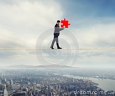 Businessman carries a piece of puzzle while he walking on a rope. concept of missing piece Stock Photo