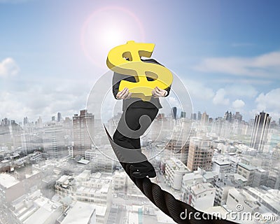 Businessman carrying gold dollar sign balancing on wire Stock Photo