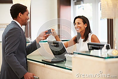 Businessman Checking In At Hotel Reception Front Desk Stock Photo
