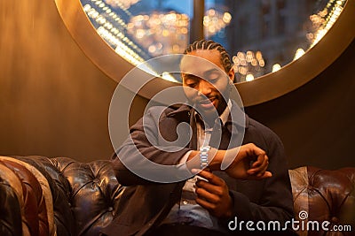 Businessman checks the time on his wrist watch, happy successful person indoors Stock Photo