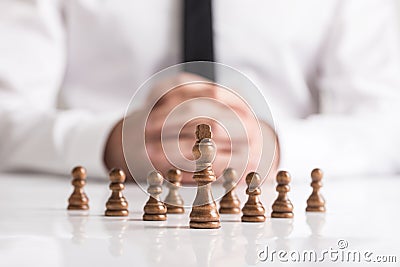 Businessman with clasped hands planning strategy with dark chess Stock Photo