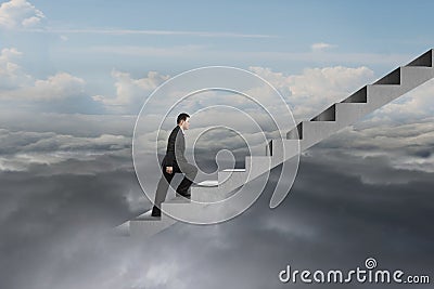 Businessman climbing on concrete stairs with natural cloudy sky Stock Photo