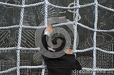 Businessman climbing crisscross rope net on business concept doodles background Stock Photo