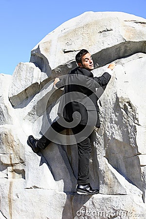 Businessman climbing a rock Stock Photo