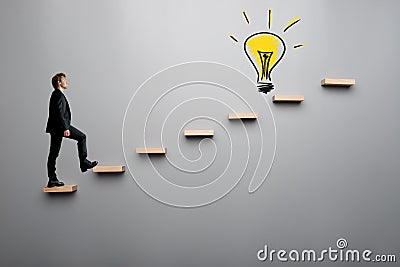 Businessman climbing steps towards light bulb Stock Photo