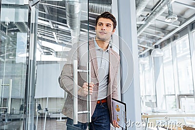 Businessman with clipboard entering the door in office Stock Photo