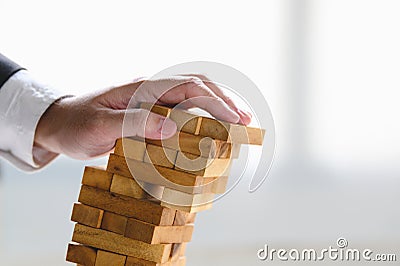 Businessman collapsing stacked tower wood block by hand as failure or bankrupt project. Business organization and company Stock Photo
